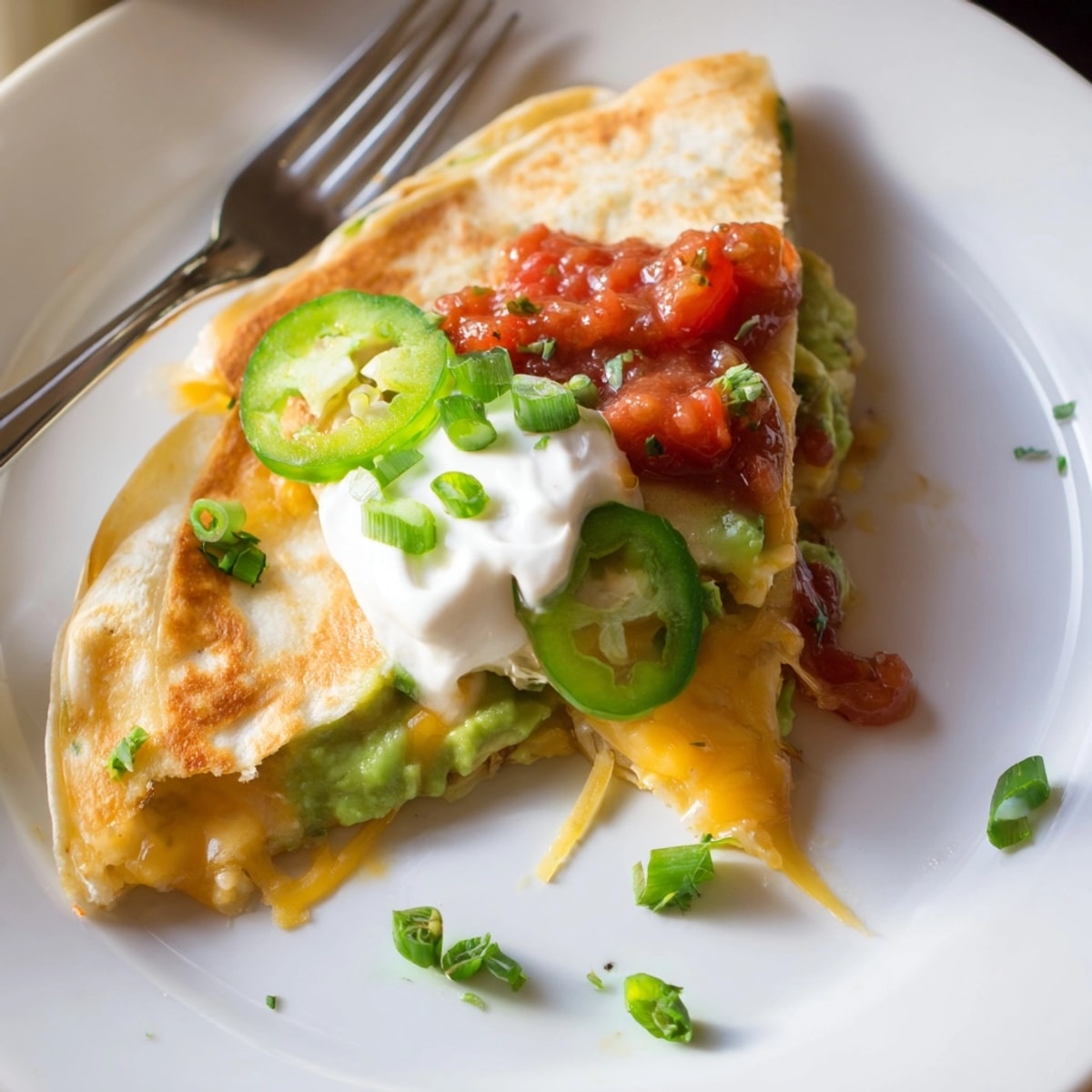 Golden Avocado Cheddar Grilled Quesadilla cut in wedges, oozing melted cheese with garnishes.
