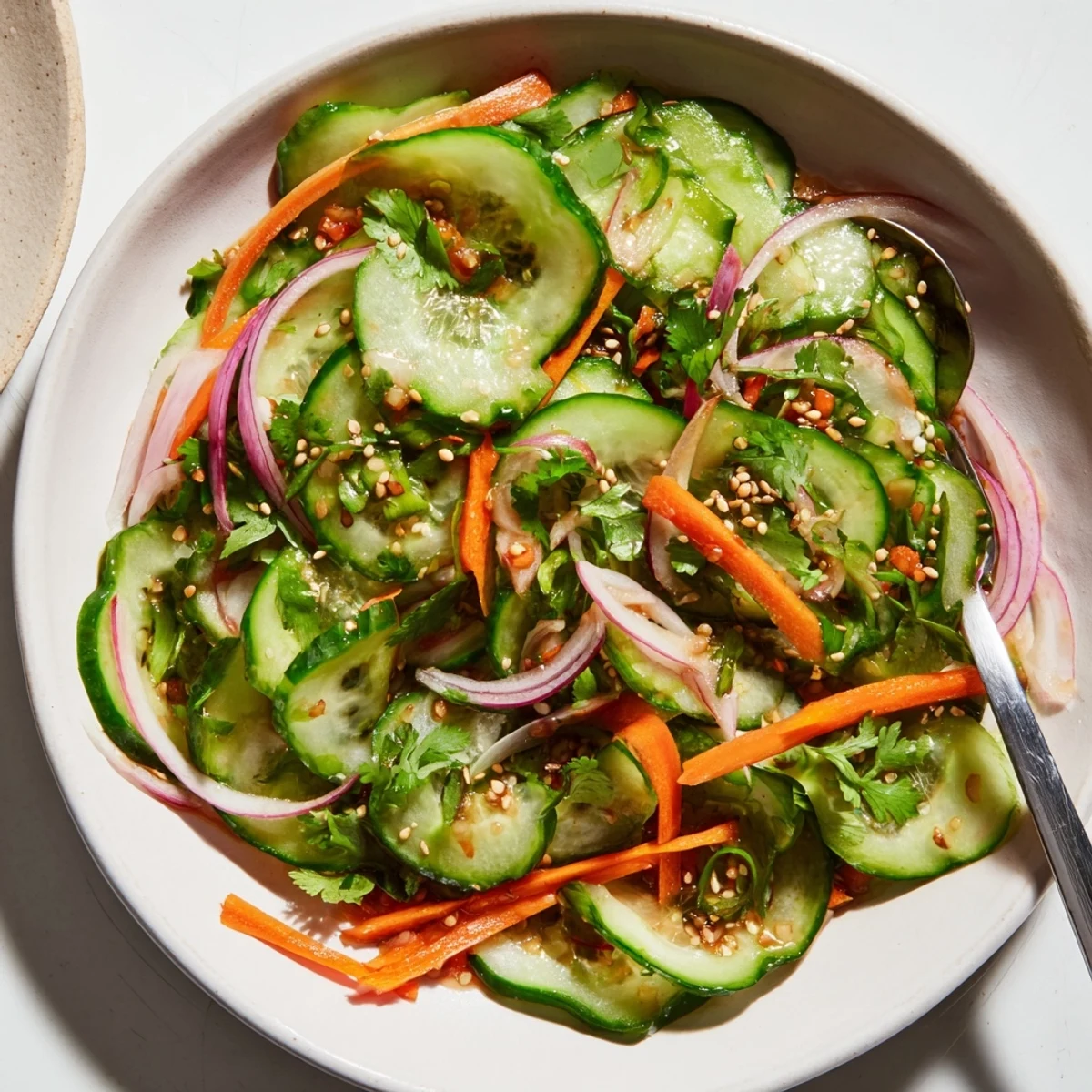 Vibrant cucumber salad remix, garnished with toasted sesame seeds and fresh vegetables.  