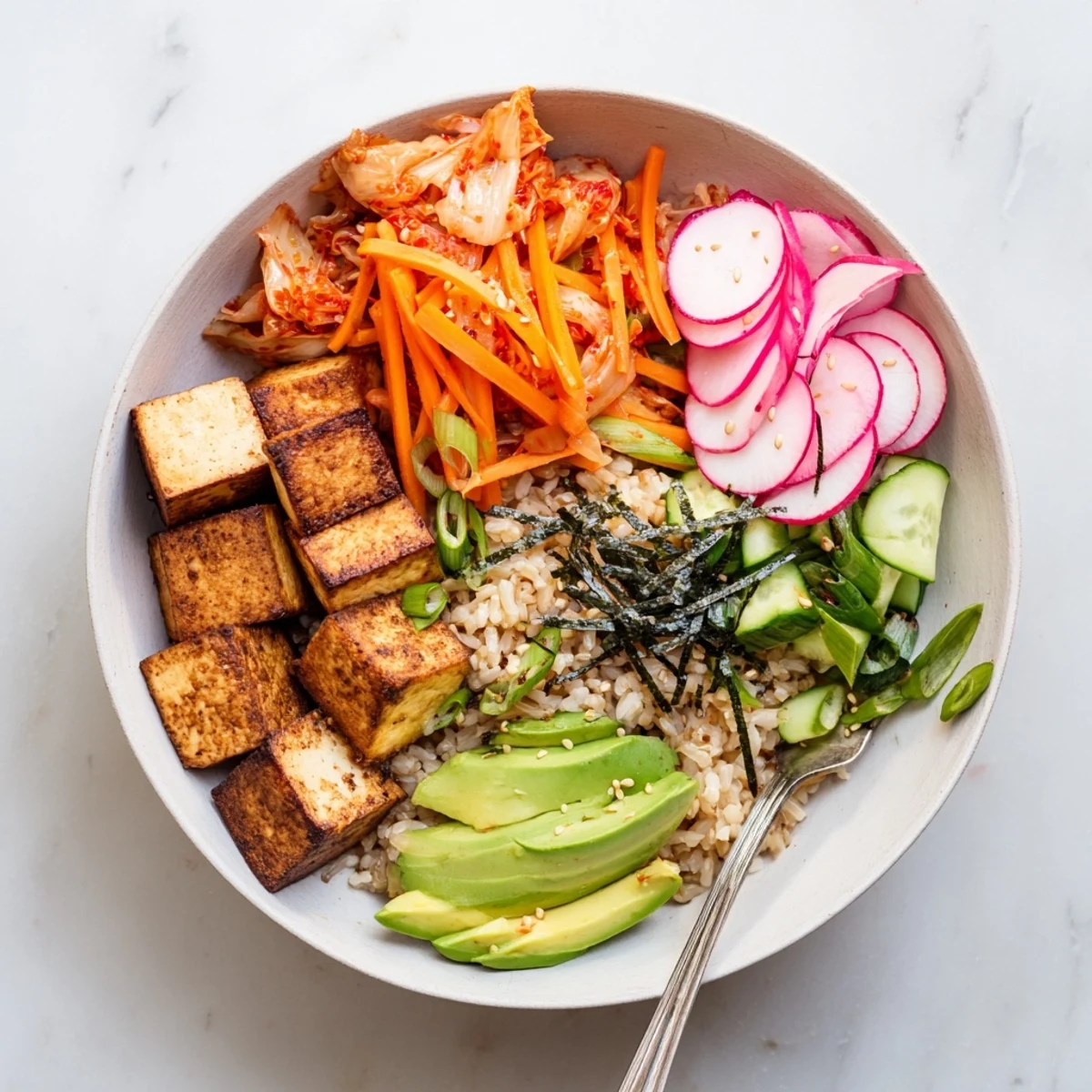 A colorful fermented vegetable bowl topped with spicy kimchi and fresh greens.  