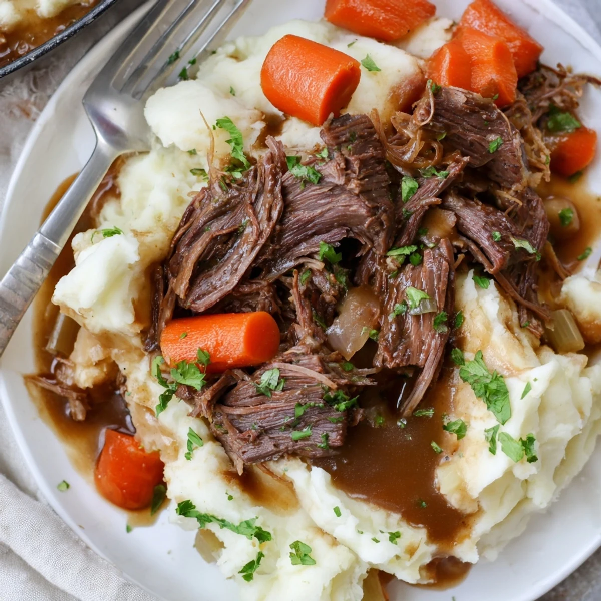 Tender Slow Cooker Pot Roast with Mashed Potatoes, garnished with fresh parsley and rich broth.