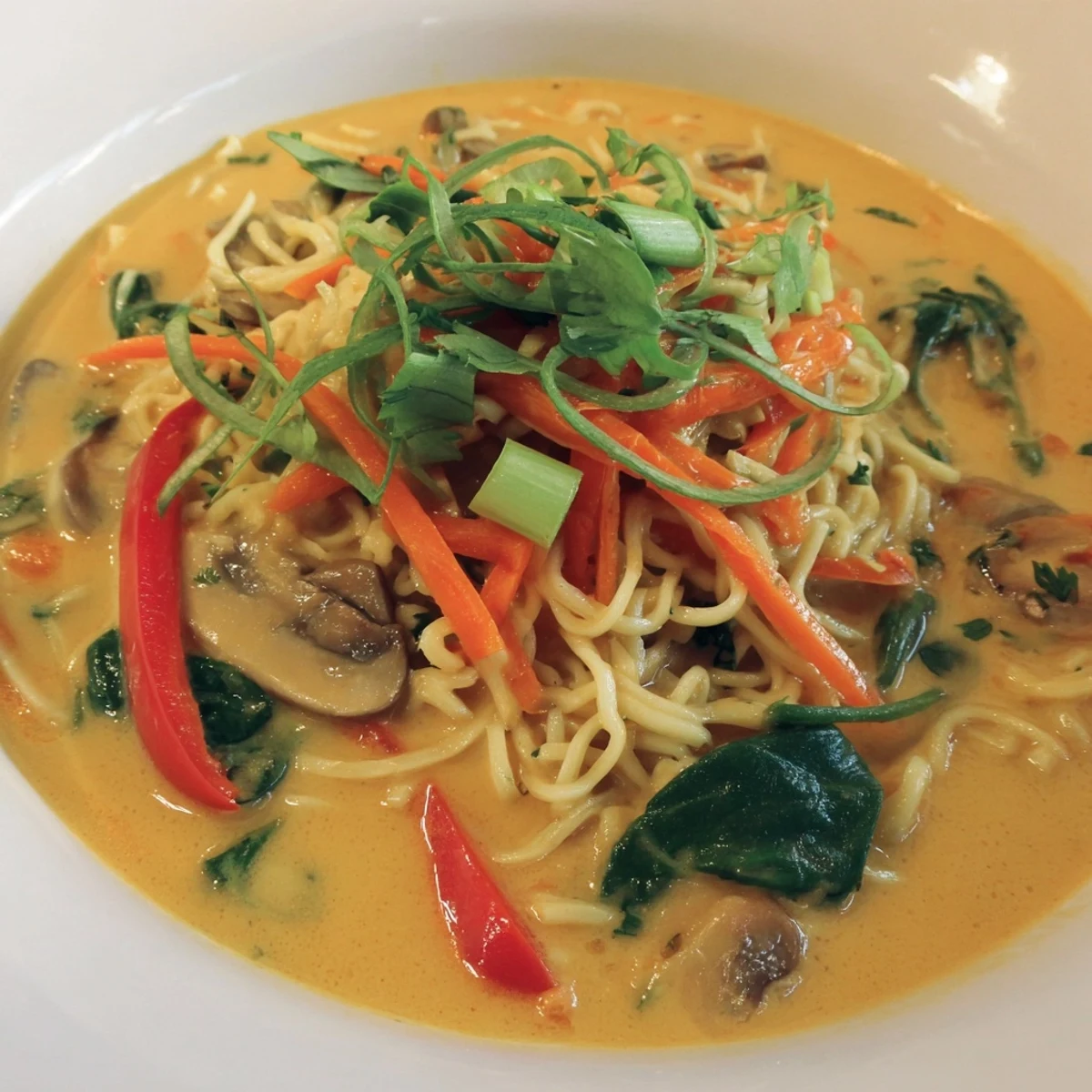 Steaming bowl of Curry Coconut Ramen with vibrant vegetables and fresh cilantro, ready to enjoy.