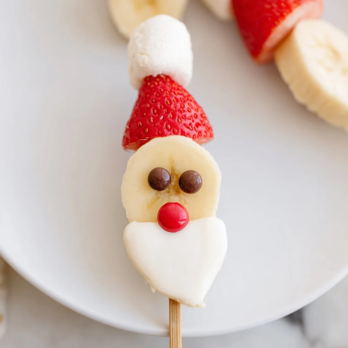 Banana Santa Snack Sticks on a skewer, with a delicious Santa face made from fruit and sweets.