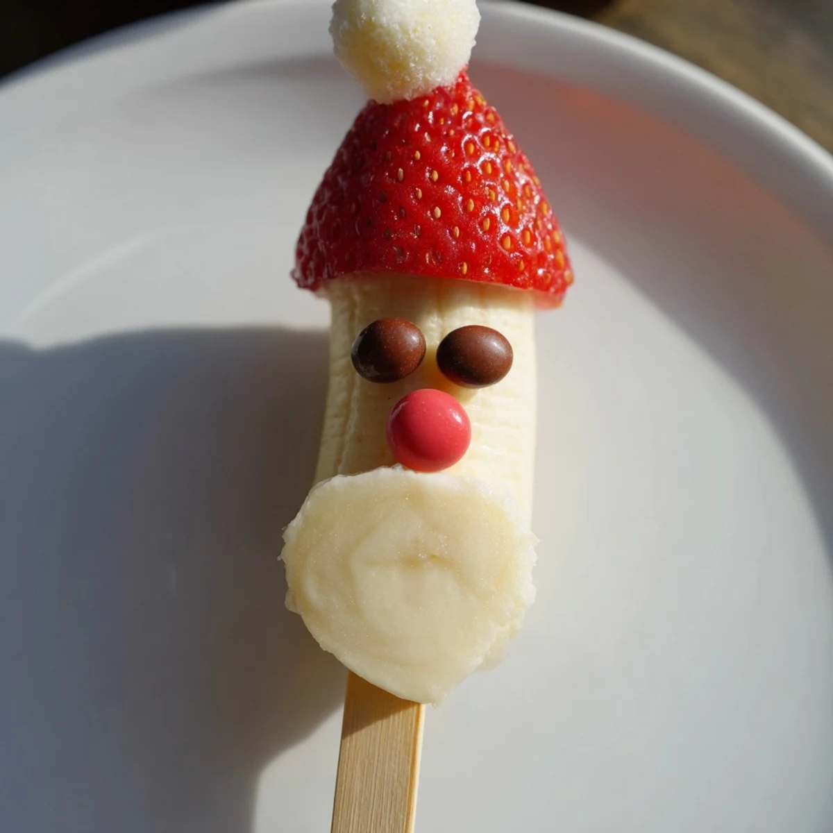 Colorful Banana Santa Snack Sticks with strawberry hats, marshmallow beards, and chocolate chip eyes.