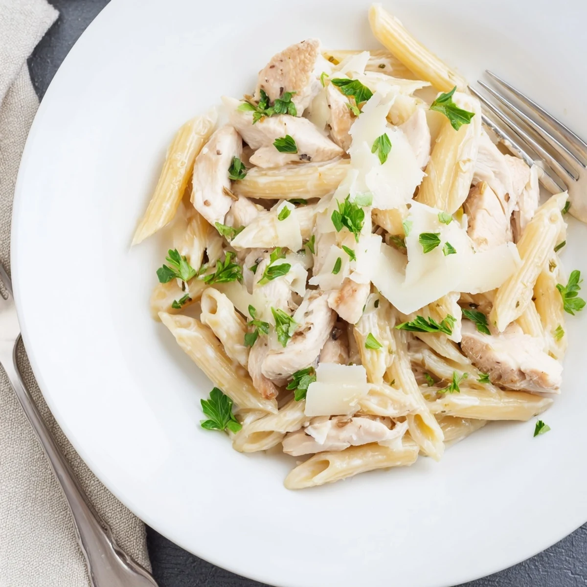 A close-up of roasted garlic chicken penne with a rich, velvety sauce and freshly grated Parmesan.  