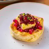 Warm, bubbly Fireworks Brie Tartlets, a festive appetizer loaded with fruity flavors and creamy Brie.