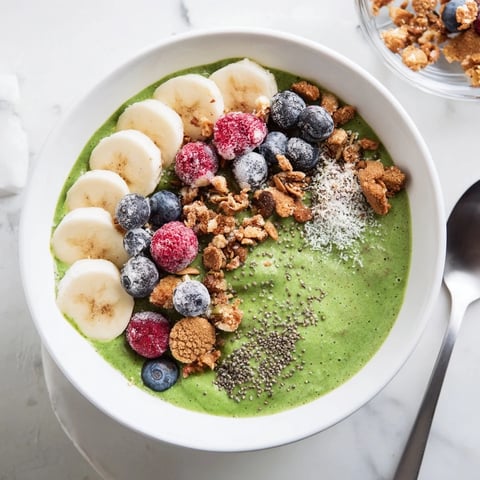 Vibrant, creamy Gingerbread Cookie Matcha Smoothie Bowl topped with colorful granola and candied ginger.