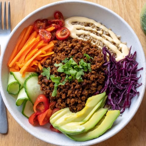 Satisfying plant-based meat bowl featuring colorful toppings and spicy mayo drizzle.  