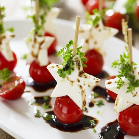 Fresh Caprese Skewers in star shapes: a delicious appetizer drizzled with balsamic glaze and olive oil.