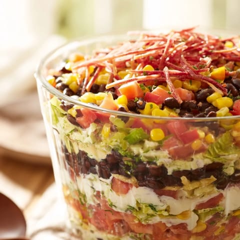 A clear glass bowl showcases the Southwest Sunset Palette, a layered salad with fresh garnishes.