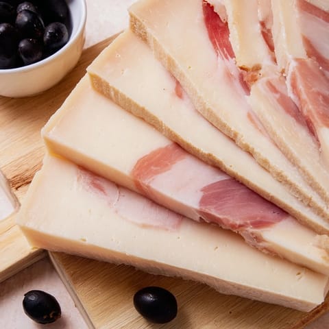 A gorgeous cheese board arrangement highlighting the flavors of fine Comté, ham, and Castelvetrano olives.