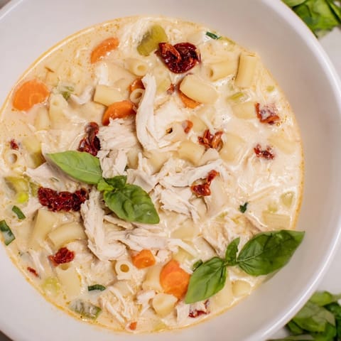 A steaming bowl of comforting Marry Me Chicken Soup, featuring tender chicken, and vibrant, creamy broth with pasta.