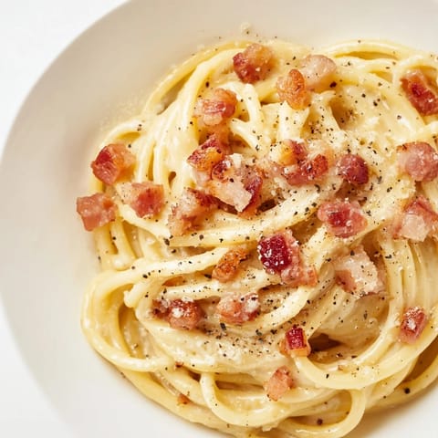 Golden, crispy bacon bits topping a fresh plate of Express Spaghetti Carbonara, ready to be enjoyed.