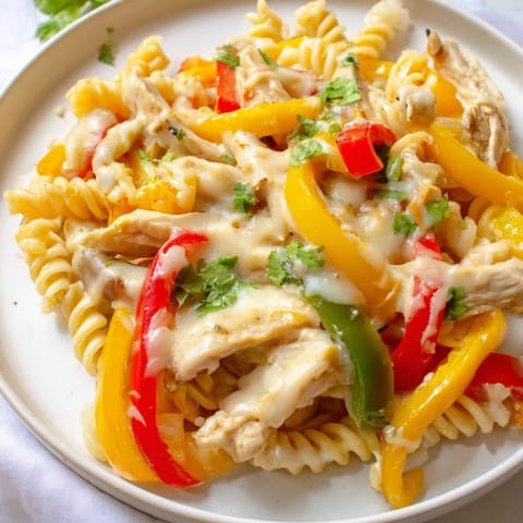 A close-up of Fajita Chicken Pasta in a cast-iron skillet shows golden pasta coated in creamy, cheesy Tex-Mex sauce.