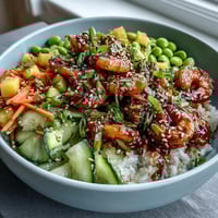 Fresh shrimp poke bowl with juicy mango, edamame, and avocado, drizzled with savory sesame-ginger sauce for a healthy Hawaiian-inspired meal.