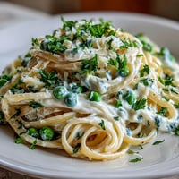 Creamy ricotta and lemon linguine with peas, bright with citrus zest and fresh herbs, ready to serve in a pasta bowl.